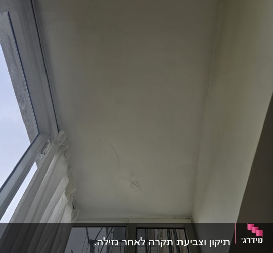 תקרה עם סימני תיקון וצביעה ליד חלון